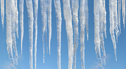 big sunlit winter icicles on bright blue sky background