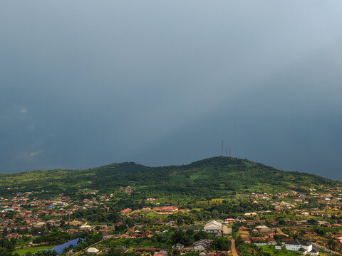 Aerial view of the dark sky contrasting with the lush green of Imo Hill and the vibrant buildings of Ilesa, Osun, Nigeria.