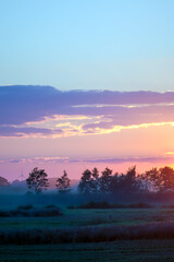 Krajobraz kolorowy zachód słońca mgła nad polami. © Monika