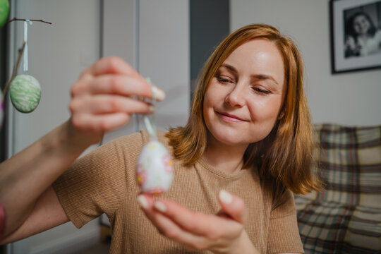 Smiling adult decorating colourful Easter egg at home