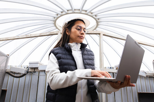 Engineer and site manager using laptop while reviewing plans indoors