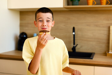 Young boy eating chocolate donut at home kitchen © djile
