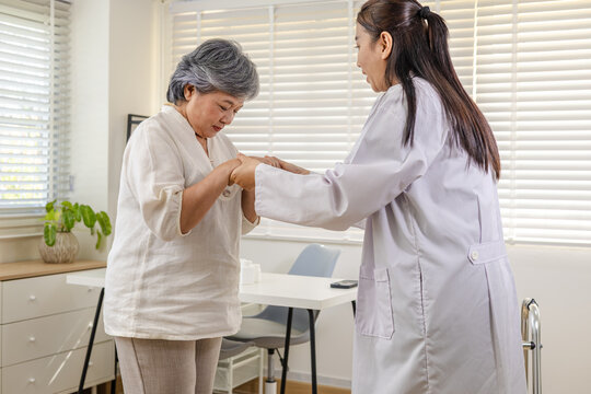 Clinic rehabilitation private care, physician encourages senior patient walking with walker, safe movement instruction, balance training, fall prevention screening, progress review appointment.
