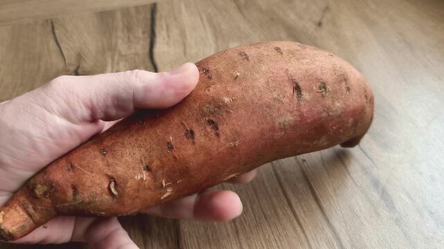 Hands holding sweet potatoes in kitchen
