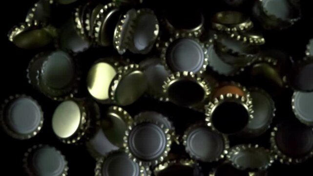 Beer Bottle Caps. Golden beer bottle caps floating in the air on a black background. Slow Motion