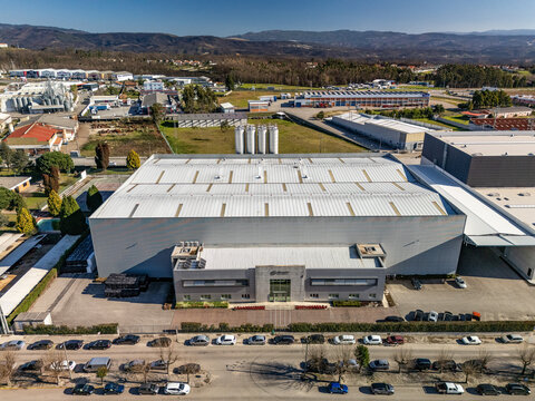 Aerial view of a large industrial building with rows of parked cars contrasting with the distant rolling hills, Albergaria-a-Velha, Portugal.