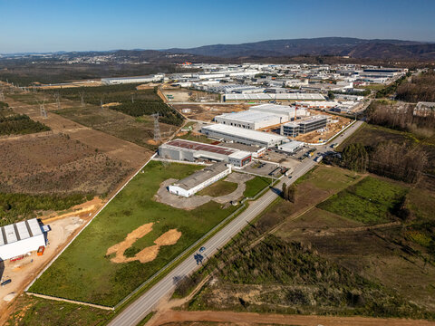 Aerial view of industrial buildings contrasting against open fields, a dynamic landscape of human enterprise and natural beauty, Albergaria-a-Velha, Portugal.