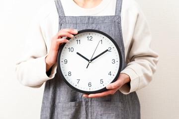 白背景に時計を持つ主婦