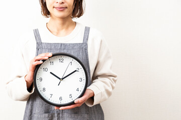 白背景に時計を持つ主婦