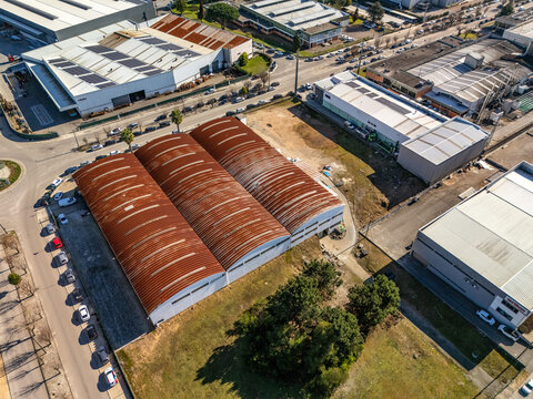Aerial view of aged warehouses stand in contrast to the modern industrial area, the weathered roofs hinting at stories of the past, Albergaria-a-Velha, Portugal.