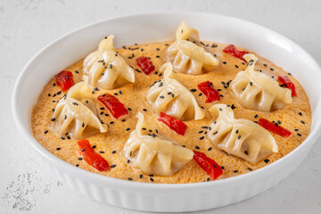 Steamed gyoza dumplings in creamy Tom Yum sauce with sesame garnish