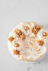 Madonna honey cake topped with toasted meringue and golden decorations flat lay