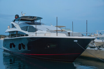 Fototapeta premium Large luxury motor yacht with dark hull and red stripe moored
