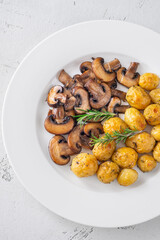 Roasted baby potatoes with sauteed mushrooms and rosemary on minimalist white plate
