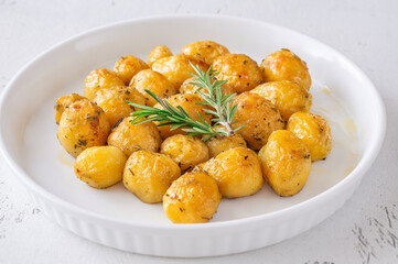 Oven baked baby potatoes seasoned with herbs served in white ceramic bowl