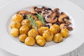 Roasted baby potatoes with sauteed mushrooms and rosemary on minimalist white plate