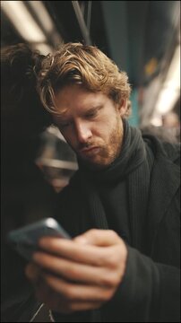 Young man using smartphone commuting on a subway train