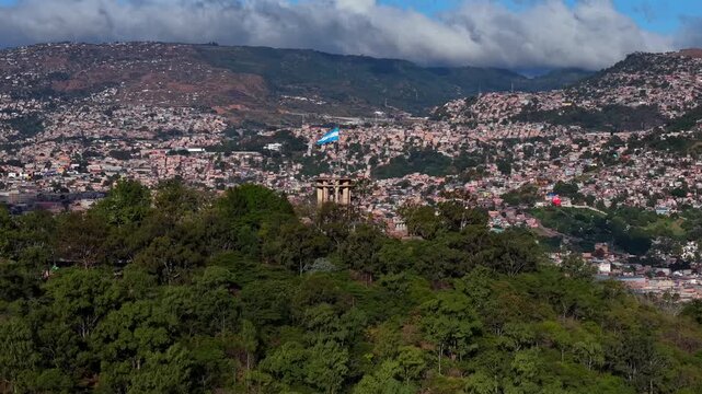Tegucigalpa Honduras - 01 26 2026: Beautiful aerial view of Tegucigalpa, capital of Honduras, with Juana hill and the Honduran flag waving, surrounded by mountains and urban valley