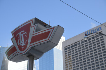 Fototapeta premium Toronto Transit Commission logo sign outside subway station at Osgoode, Queen & University (with defocused view of Hilton hotel sign)