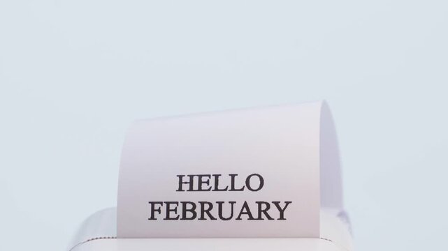 The phrase HELLO FEBRUARY is printed on a white background, close-up