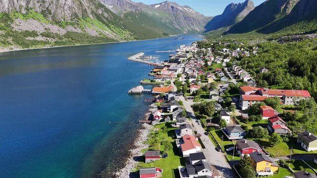 14 july 2025, Gryllefjord, Norway. Aerial, forward drone flight above village, during summer. Mountains left en right side and in background. Streets and houses, small town on Senja island.
