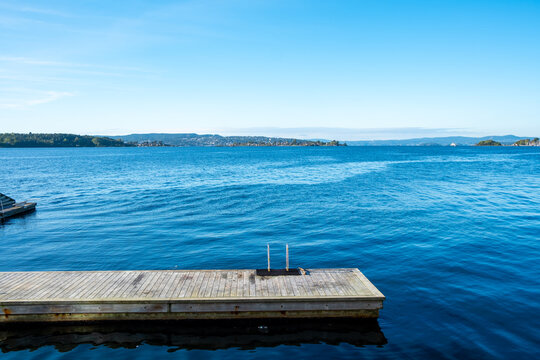 pier and dock on Oslo Norway fjord with waterfront water and tranquil seascape stretching to the horizon in clear daylight and still air