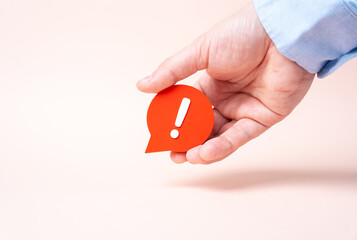 A hand holds a comment with an exclamation mark. A harsh comment, a sharp reaction. A complaint and...