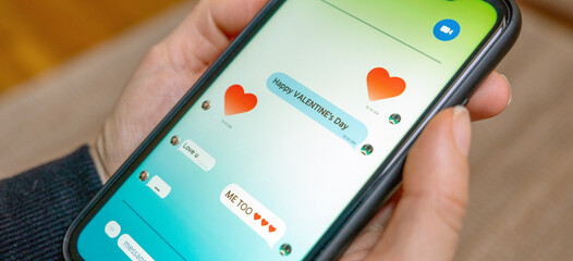 Hands holding smartphone with Valentine's Day greetings on screen close-up photo. © Barillo_Images