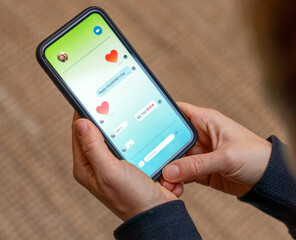 Hands holding smartphone with Valentine's Day greetings on screen © Barillo Images
