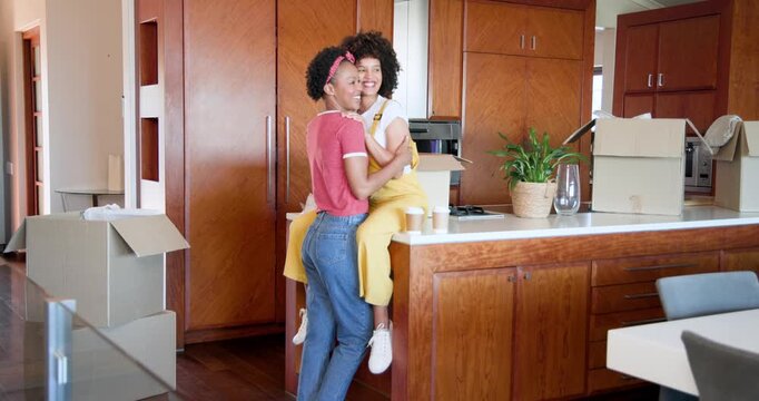 African American women embracing joyfully in kitchen surrounded by moving boxes
