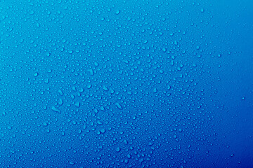 Water droplets on a blue surface create a textured pattern during a cool morning