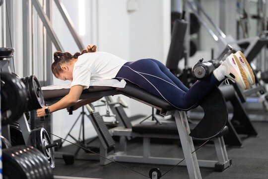 Woman exercising hamstrings on leg curl machine in a gym