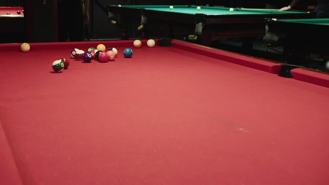 Fast break shot scatters racked billiards balls across red table, white cue ball slams triangle causing colorful pieces to fly, dynamic hit by cue captures nightlife energy during match in club