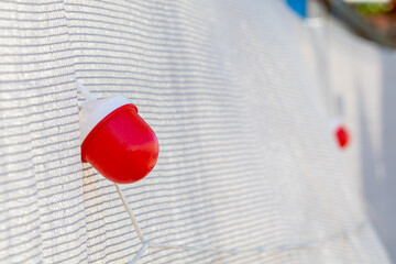 Bright red signal lantern is mounted on a light-coloured striped fabric. The lantern is part of a string light system, designed to mark hazardous areas or guide attention. The image captures the funct