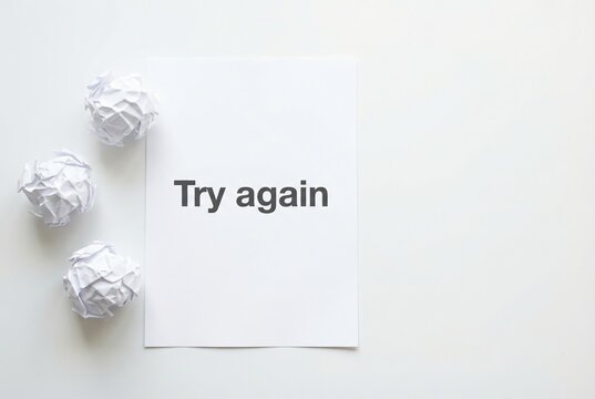 Crumpled paper beside a clean sheet reading &ldquo;Try again.&rdquo; Visual metaphor for failure, resilience, learning, and second chances.
