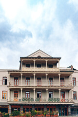 Obraz premium Historic building with balconies under a cloudy sky in a city setting