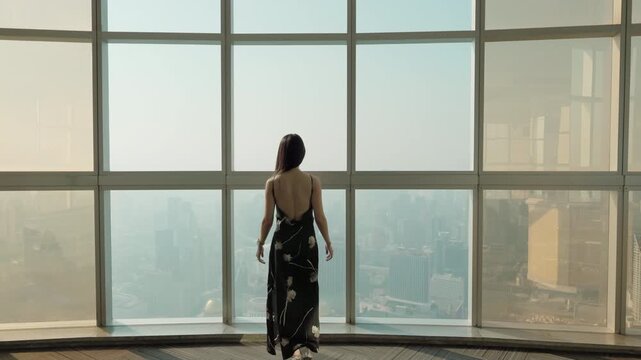 Asian stylish woman visiting in observation deck and modern glass window in skyscraper at Bangkok