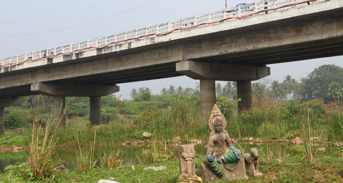 View of  Damaged statue of a female deity near a river bank in Tamil Nadu kodiveri dam and bridge over the river