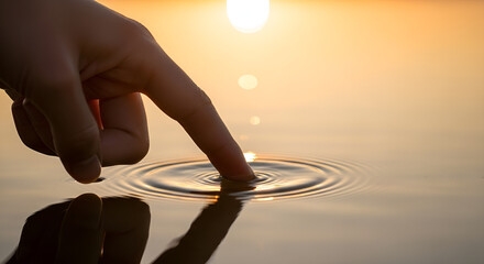 Finger touching calm water creating ripples at sunset, symbolizing a free and clear mind concept