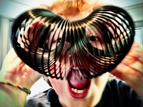 Playful portrait with face framed by coiled metal spring toy