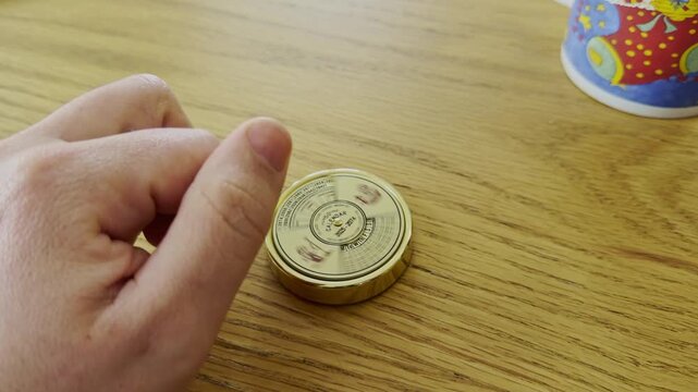 Close-up of a person's hand rotating a brass 50-year perpetual calendar wheel on a wooden desk to calculate future dates and days of the week.