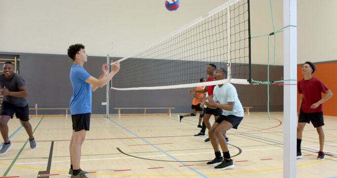 African American man practicing sets after toss while blockers jumping at gym net drill, copy space