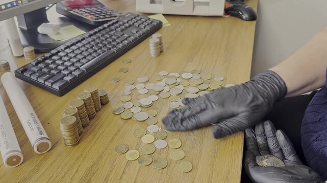 Close-up of a professional numismatist or financial auditor wearing black nitrile gloves while organizing and stacking shiny gold coins on a dark wooden surface. The shot captures a methodical process