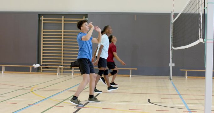 Ball drifting over net leading Diverse volleyball team practicing forearm, underhand passing at gym