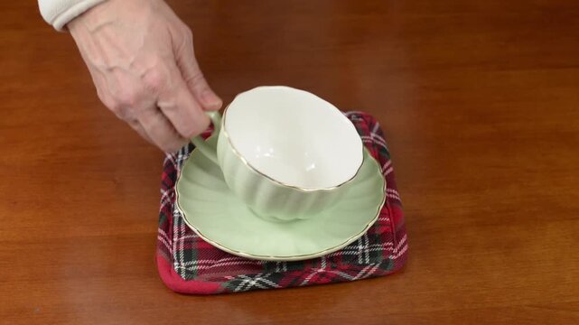 Lifting and setting down a porcelain tea cup with pauses with sound