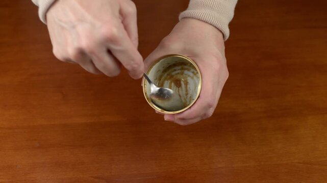 Metal spoon scraping bottom of a tin can with sound