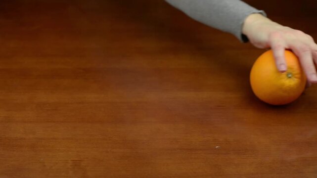 Orange rolling across a wooden table surface with sound