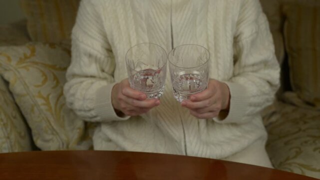 Gently clinking two crystal water glasses one to another with sound