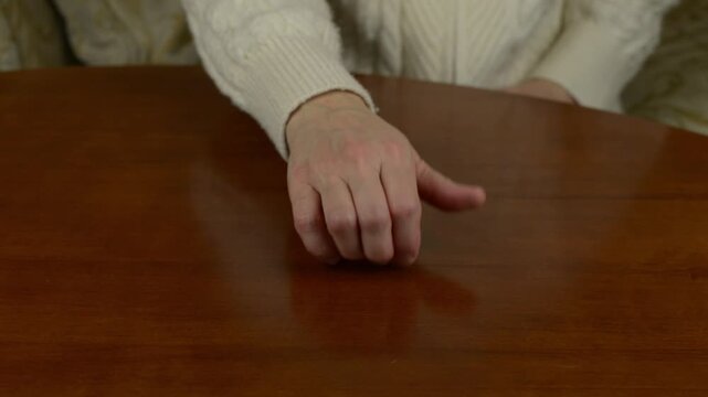 Fingernails tapping on a wooden table. Close up of nails hitting wood, rhythmic clicking sound.