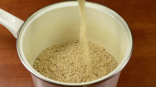 Pouring dry rice into an empty metal pot with sound